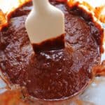 Chili Paste in a blender while a white spatula is being dipped into the chili paste.