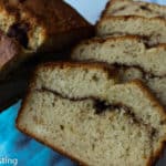 Sliced banana bread next to half a loaf of banana bread on a blue background.