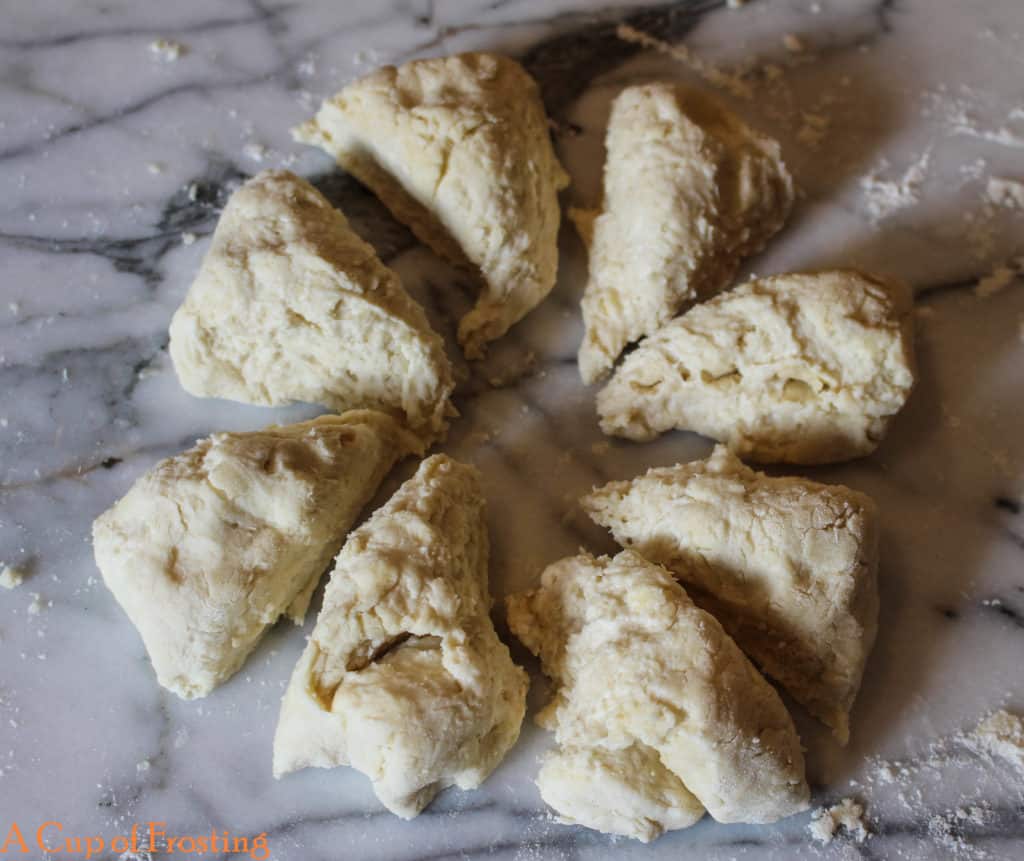 Ball of shortcake dough cut into 8 pieces creating 8 triangles on a white marble background.