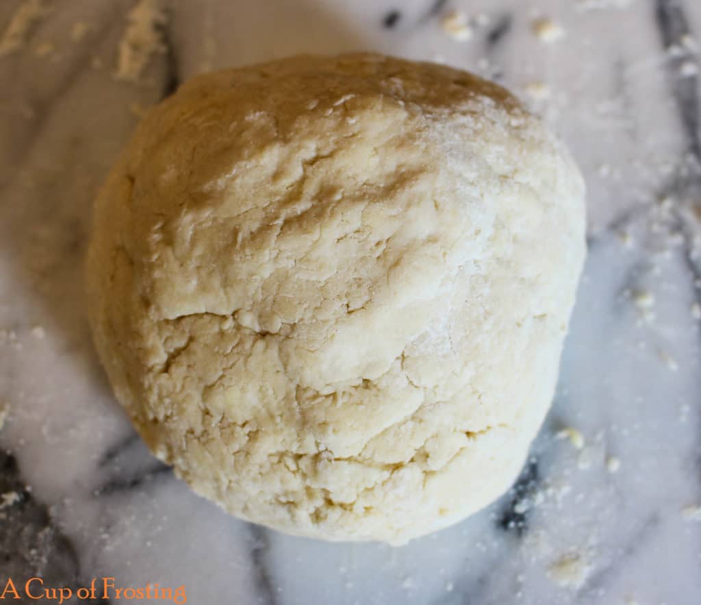 Ball of shortcake dough on a white marble background.