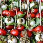 Grape tomatoes, small mozzarella ball, basil leaves alternating on small wooden skewers with pesto sauce dripped on top - 2.
