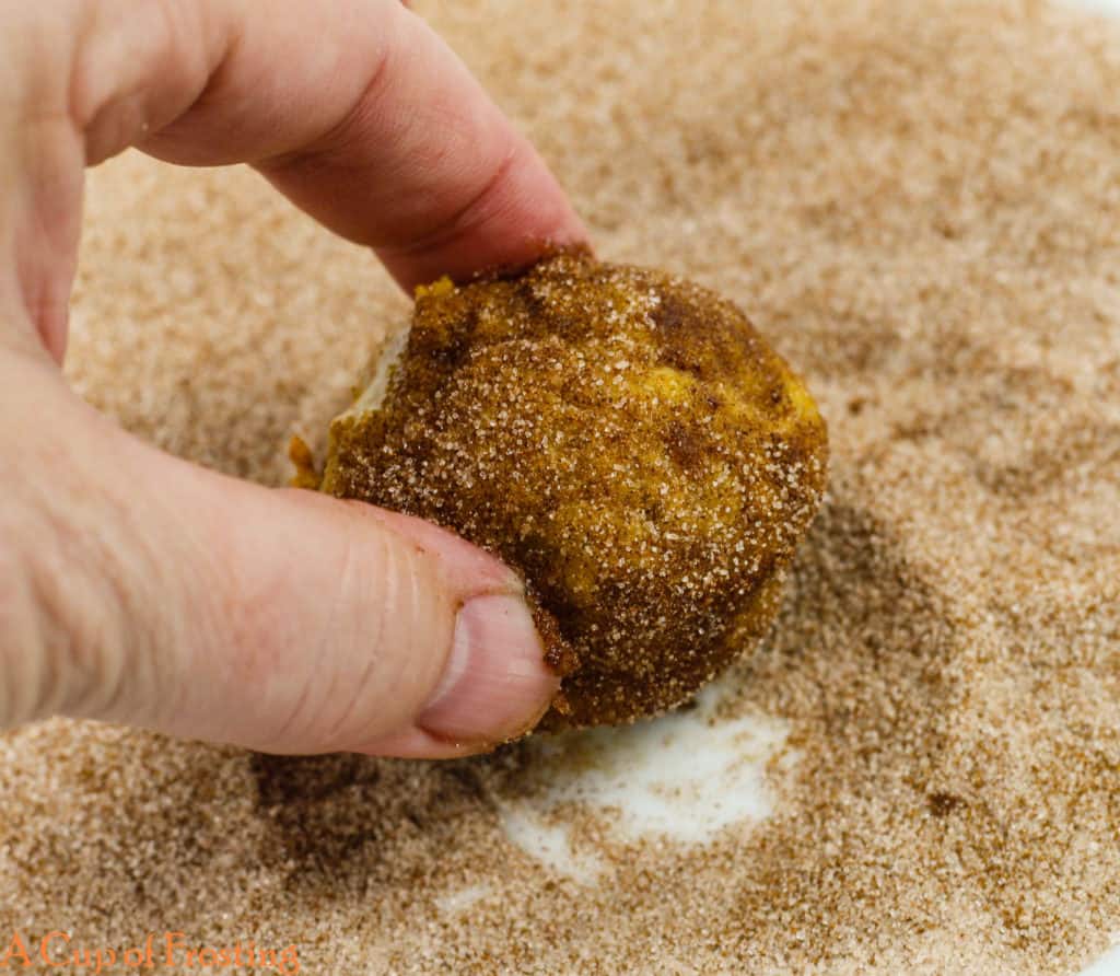 No Fry Pumpkin Donut Holes being rolled by hand in a pile of cinnamon sugar