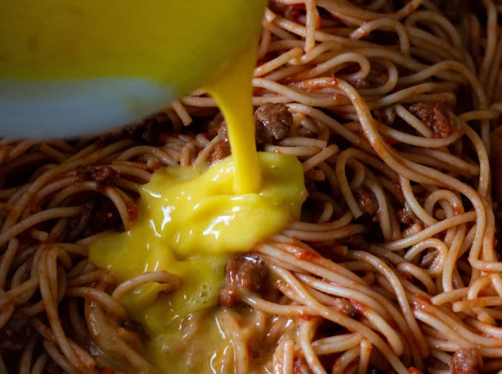 Pouring Whisked Eggs Into Sausage Sauce and Spaghetti Noodle Mixture_2