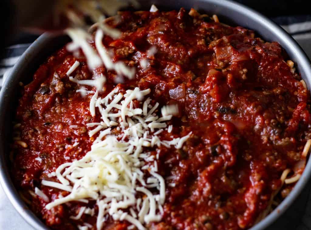 Spreading Shredded Mozarella Cheese on Top of Sausage Sauce Mixture